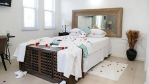 Une chambre à coucher avec un lit, une table de chevet, un miroir et une plante en pot.