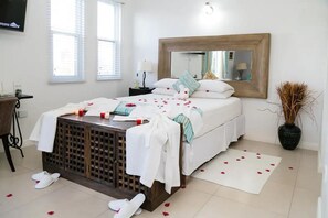 Een slaapkamer met een bed, nachtkastje, spiegel en een potplant.