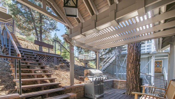 A covered outdoor area with a grill, wooden steps, and a bench.