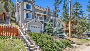 A multi-story house with a front garage, a staircase leading to the entrance, and a wooden fence.