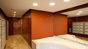 Une salle de bain moderne avec un sol en marbre, un grand miroir et une baignoire intégrée au mur, dont le design est orné de petits galets.
