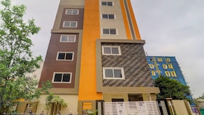 Un immeuble à plusieurs étages doté d’une architecture moderne, caractérisé par une combinaison de briques et de crépi sur sa façade.