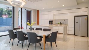A modern kitchen with white cabinets, a built-in oven, and a stainless steel refrigerator. - Ekkamai Villa Sleeps 12 with Cinema (Bangkok)