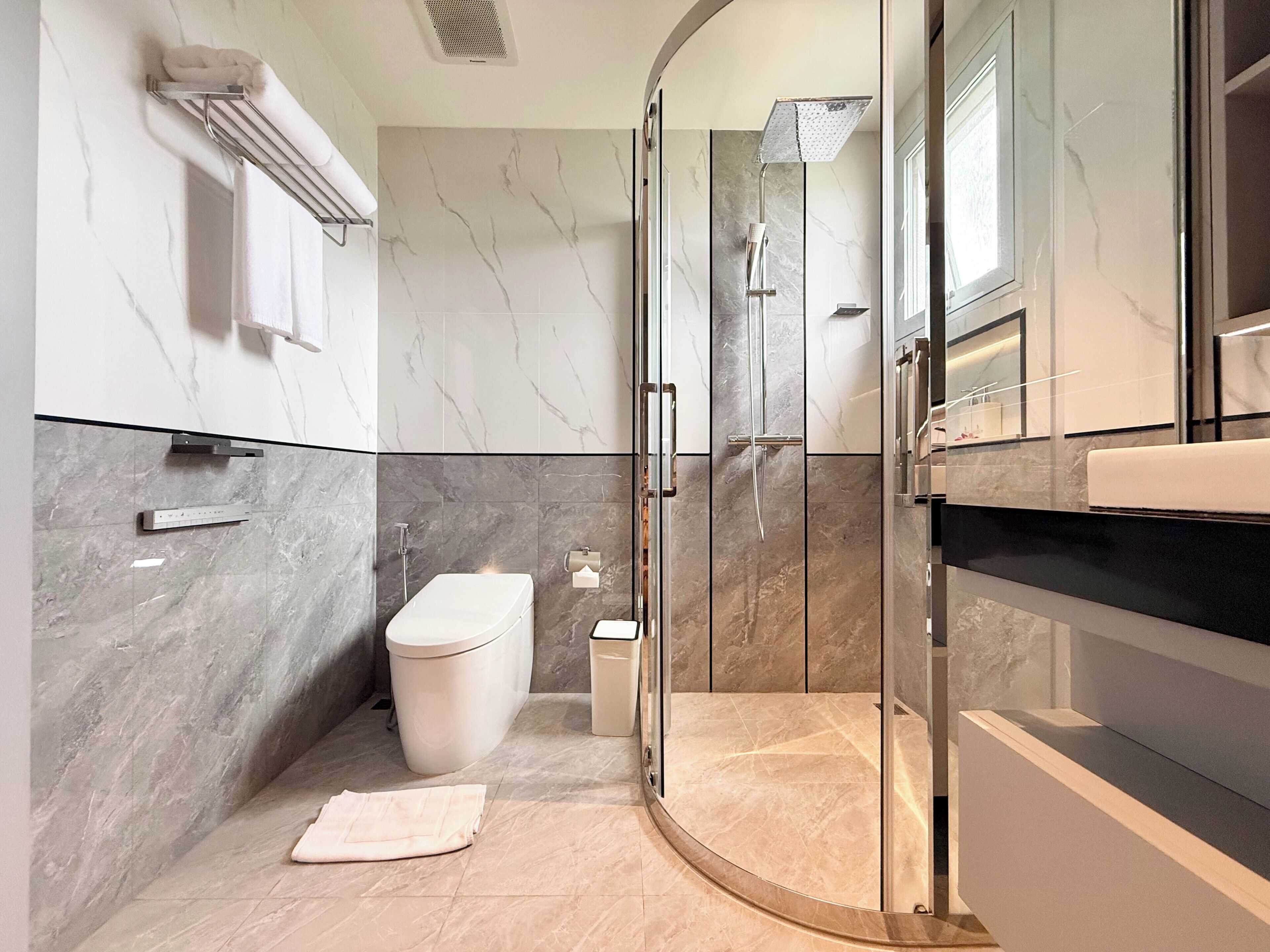 A modern bathroom with a glass-enclosed shower, a toilet, and a vanity with a mirror.