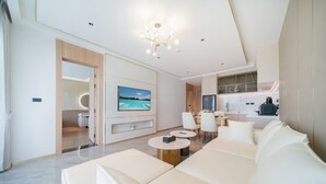 A modern living room with a sofa, a TV, and a dining area. - Chalong Marina Bay View Phuket (Rawai)