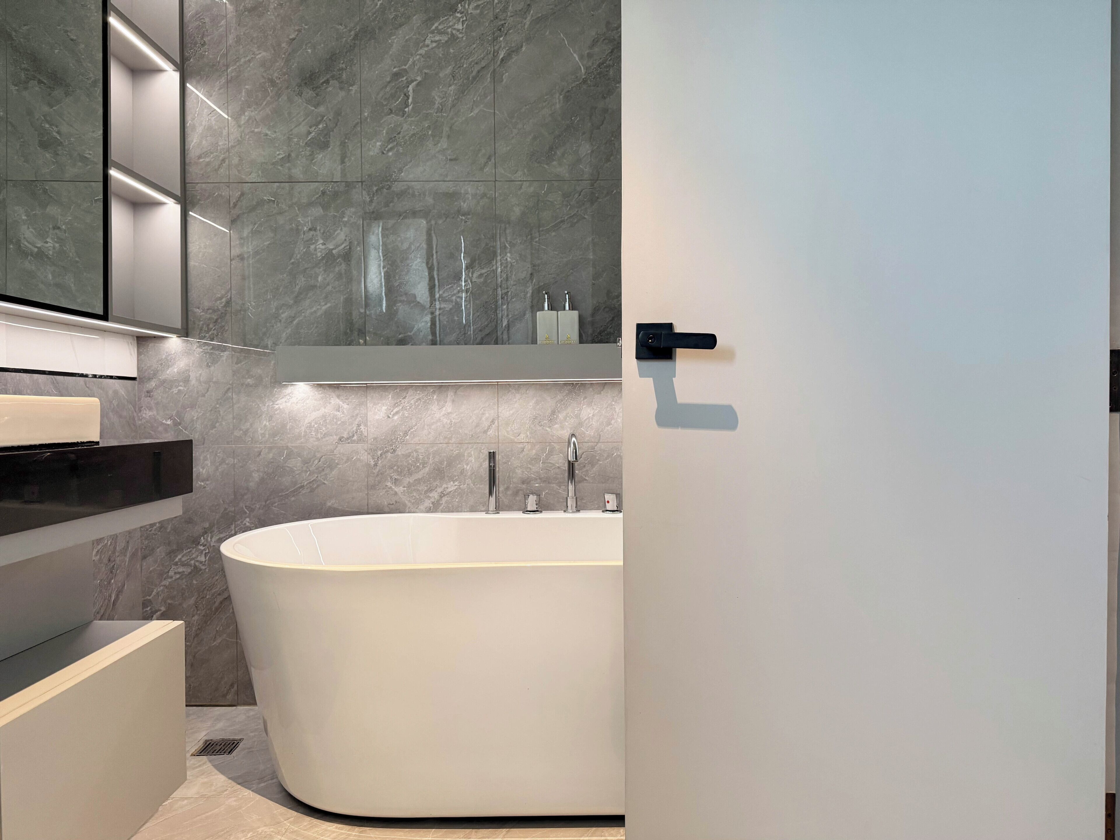 A modern bathroom with a freestanding bathtub, a mirror, and a sink.