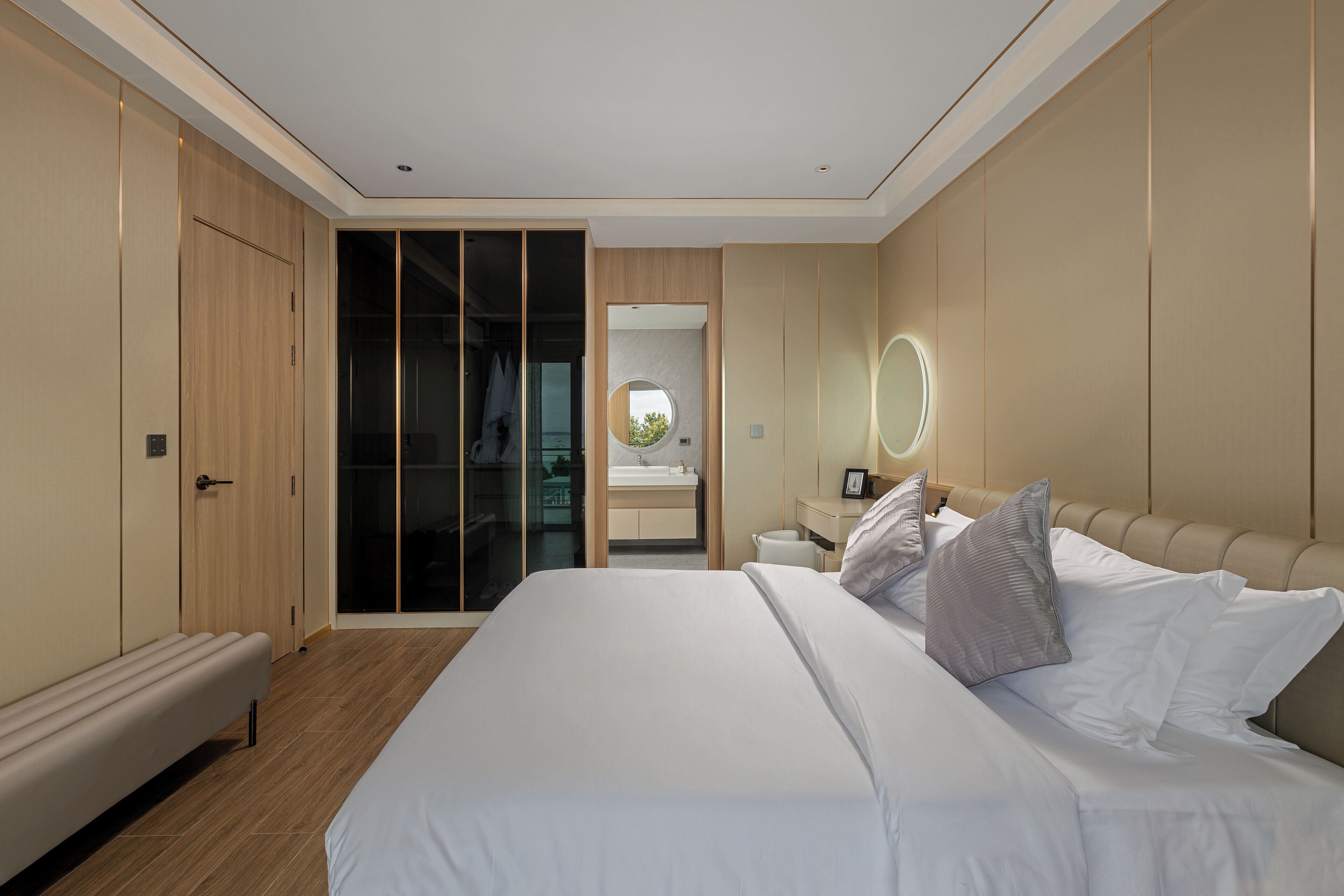 Ein modernes Schlafzimmer mit einem großen Bett, einem Nachttisch, einem Spiegel und einem begehbaren Kleiderschrank.