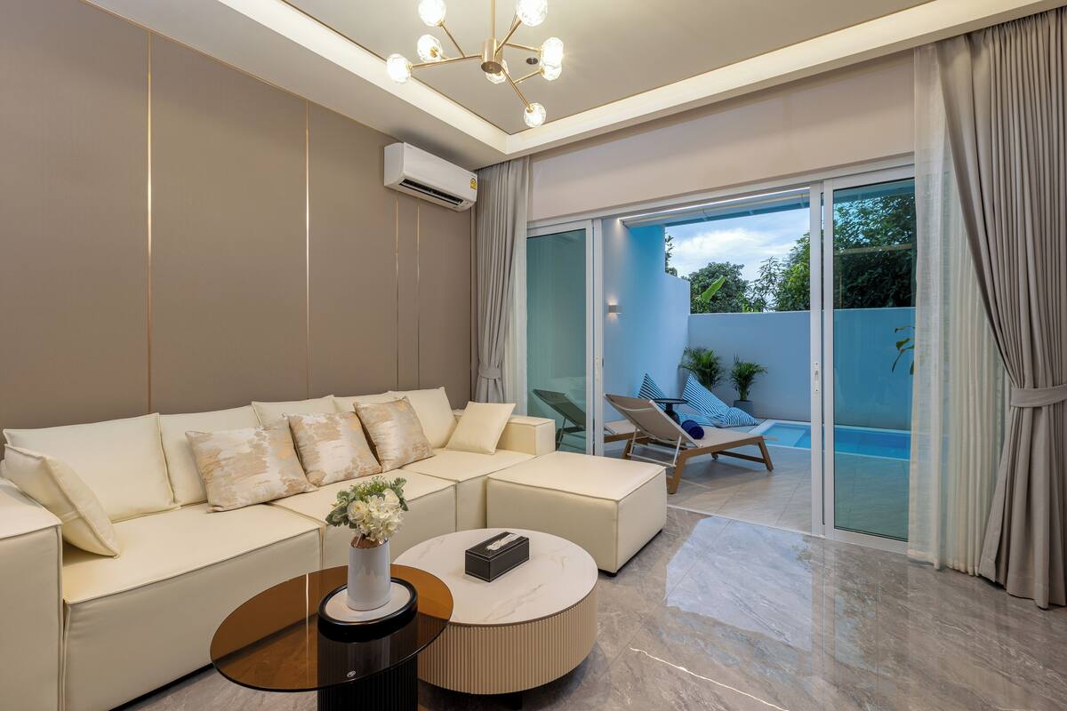 Ein modernes Wohnzimmer mit einem weißen Sofa, einem runden Couchtisch und einer Glastür, die auf einen Balkon führt.