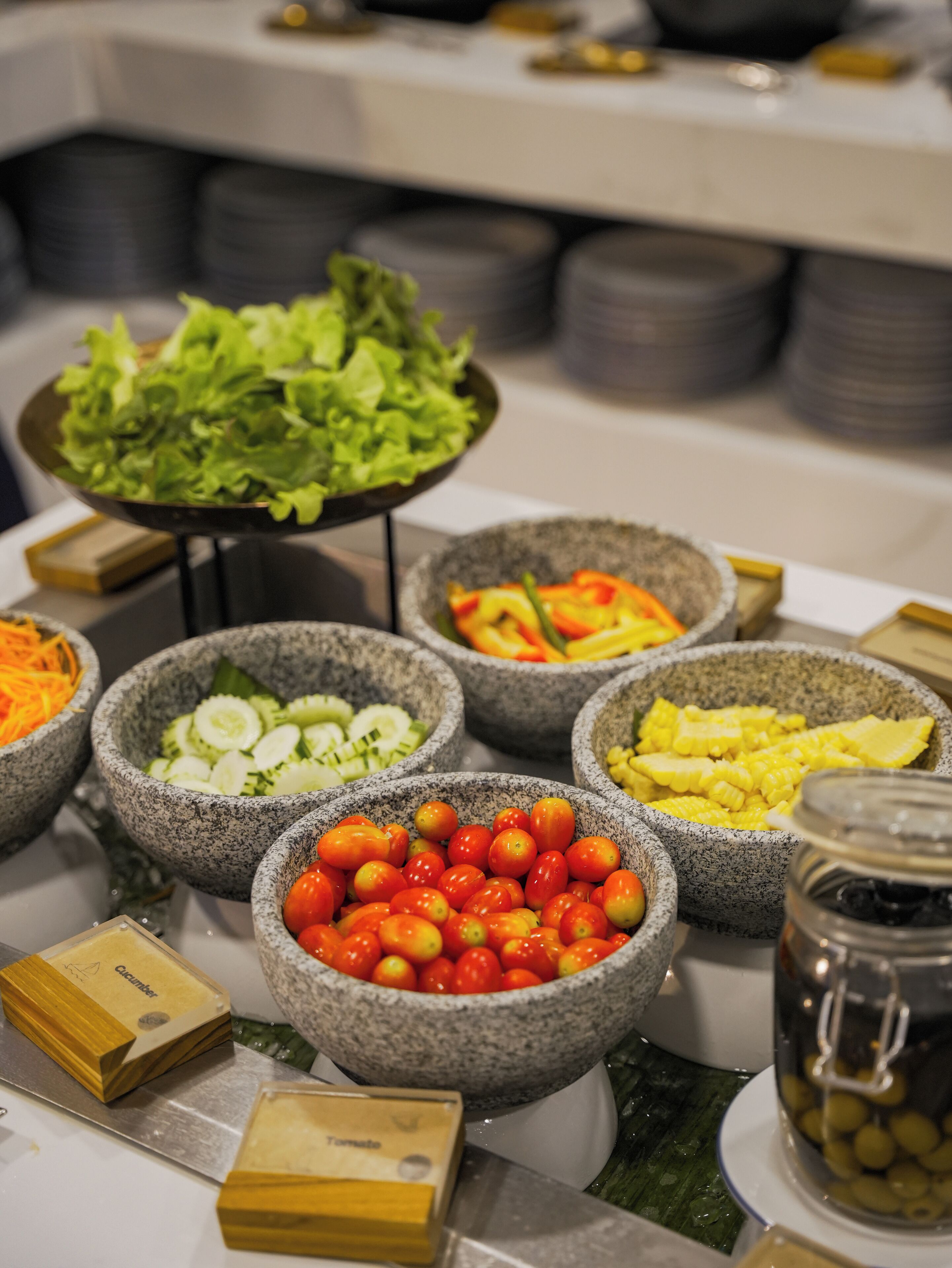 En buffet med forskellige retter i stentøjsskåle, blandt andet grøntsager og tomater.