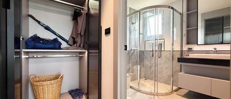 A modern bathroom with a glass shower enclosure, a large mirror, and a wooden floor.