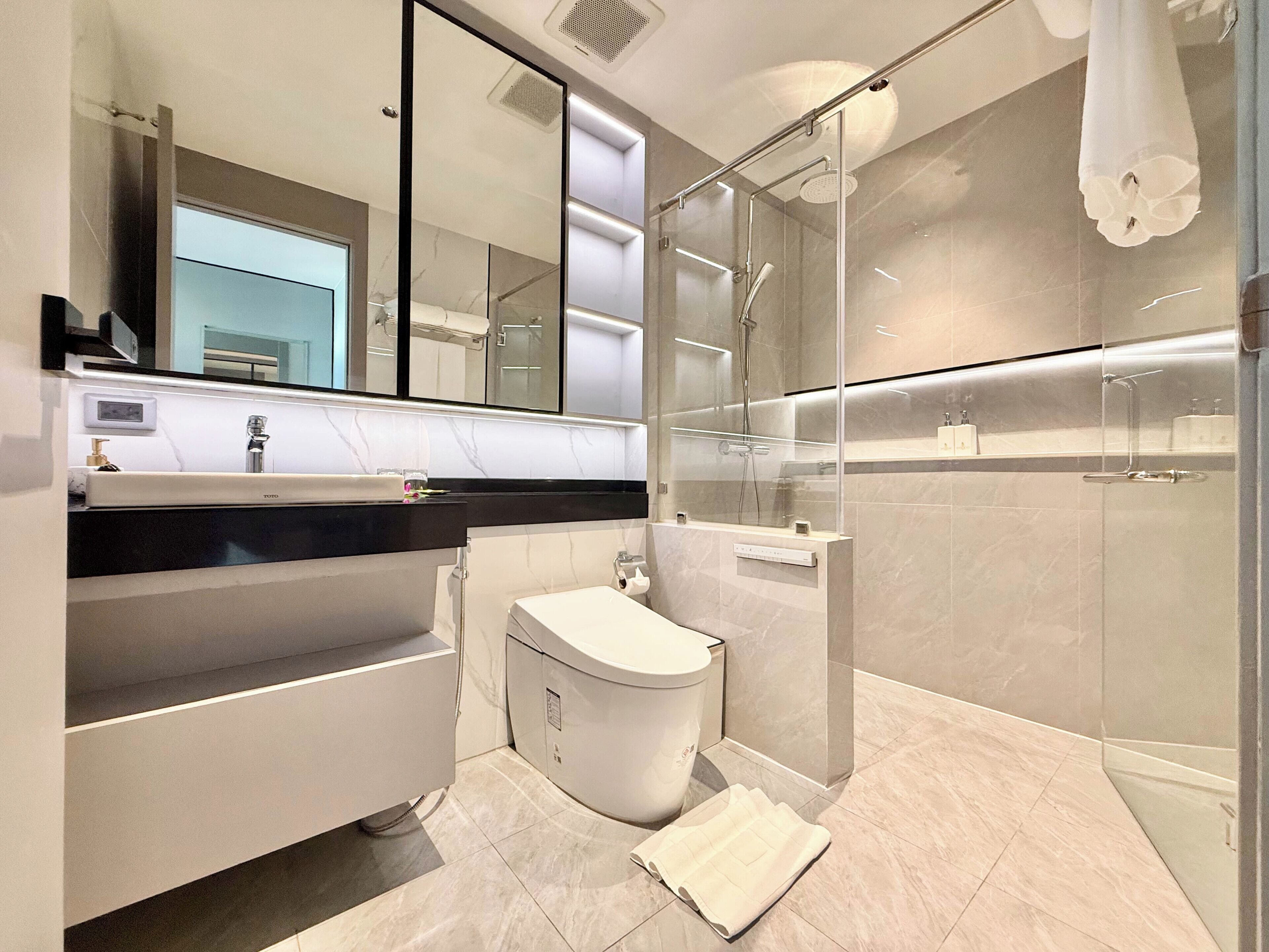 A modern bathroom with a glass shower enclosure, a white sink, and a large mirror.