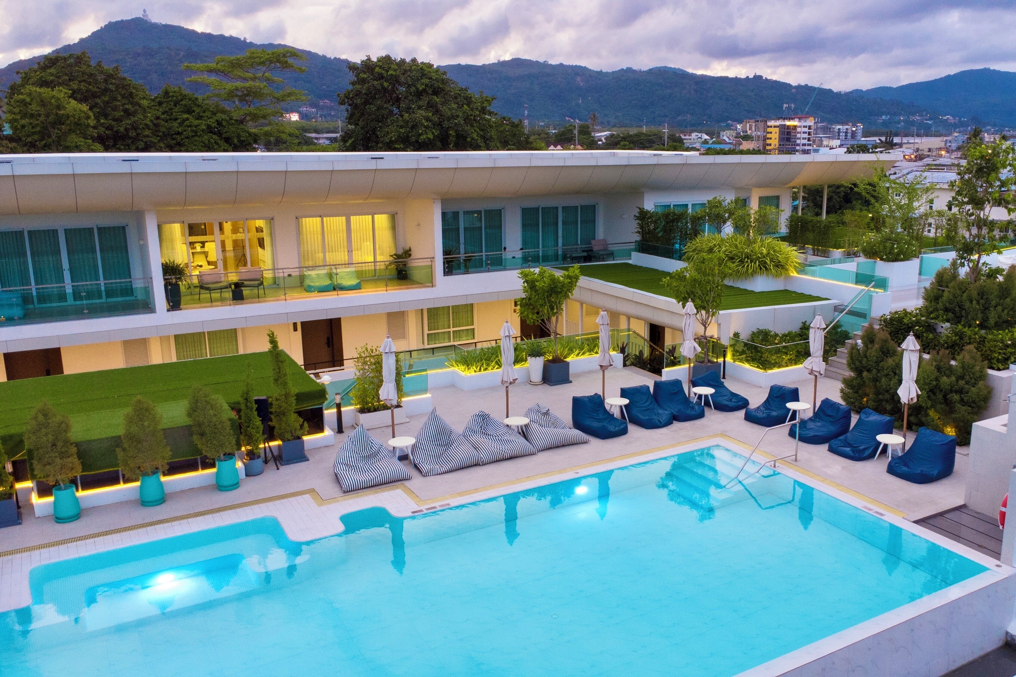 Un hotel modern amb una zona de piscina, seients a l'aire lliure i vistes a les muntanyes.