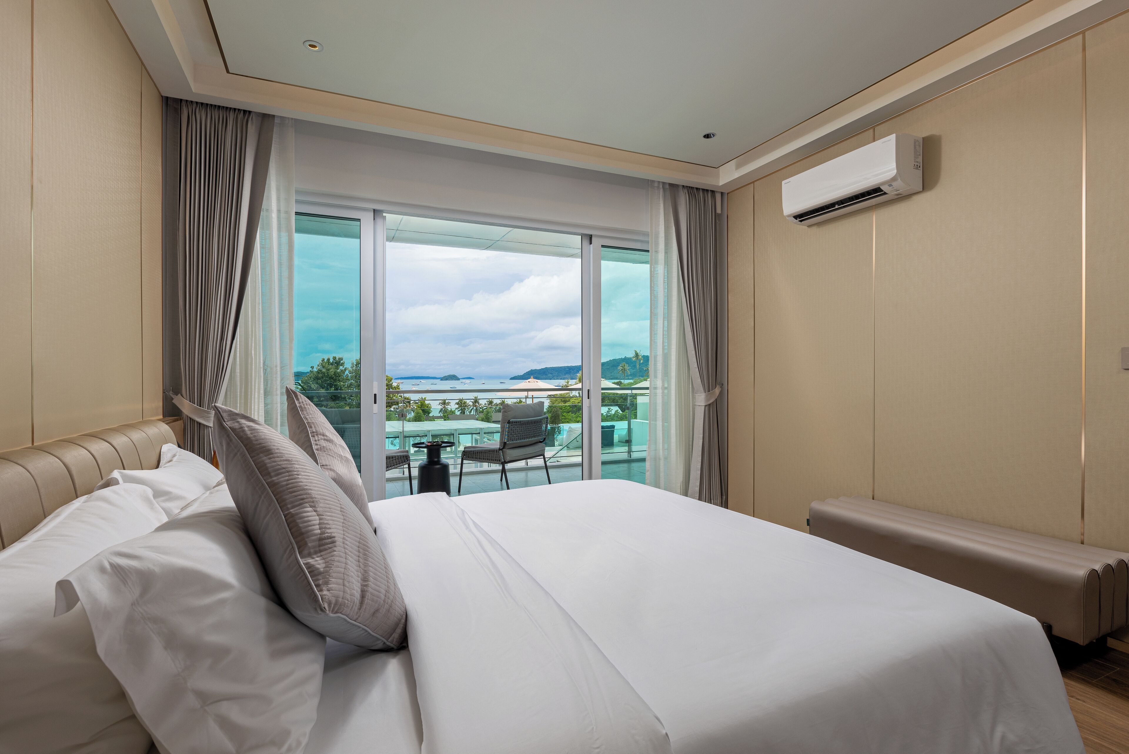 A modern hotel room with a large bed, a view of the sea, and an air conditioning unit.