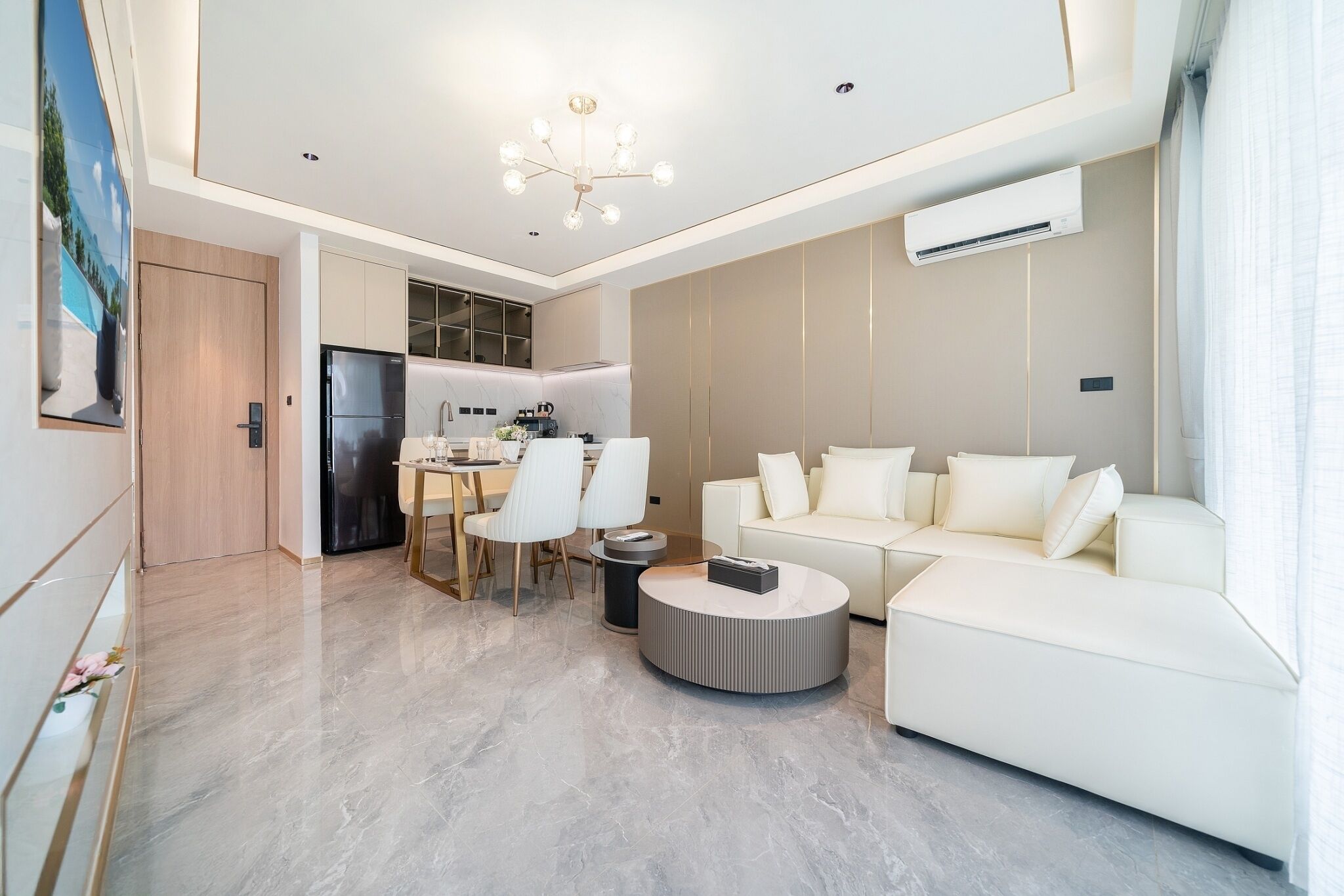 Un salon moderne avec un canapé blanc, une table basse ronde et un coin repas comprenant une table et des chaises.