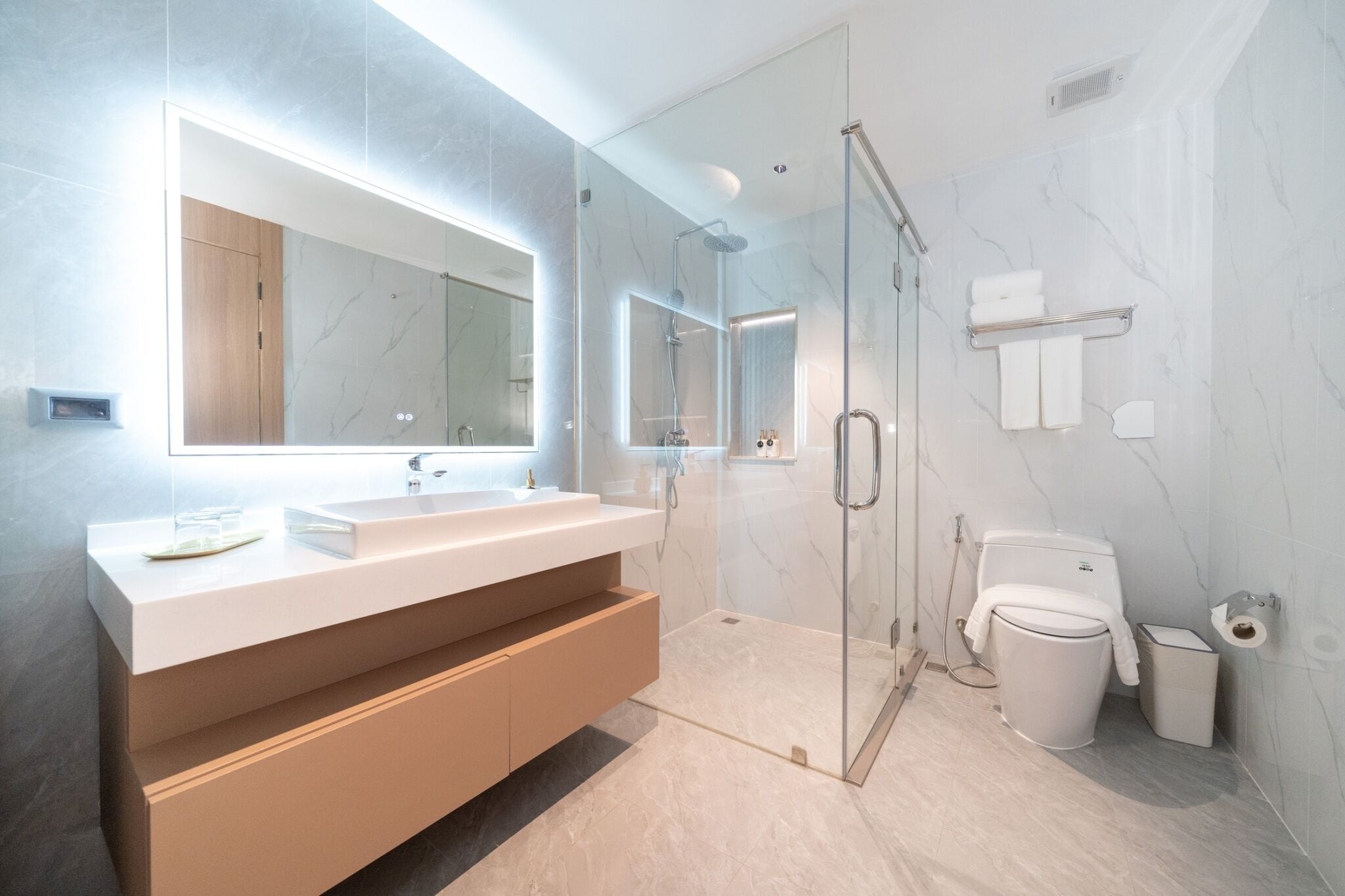 A modern bathroom with a glass-enclosed shower, a white sink, and a large mirror.