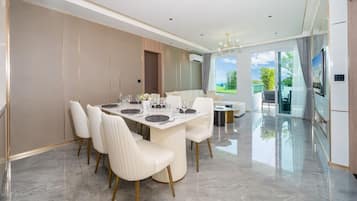 Un comedor moderno con una mesa grande dispuesta para seis personas, rodeada de sillas blancas con patas doradas.
