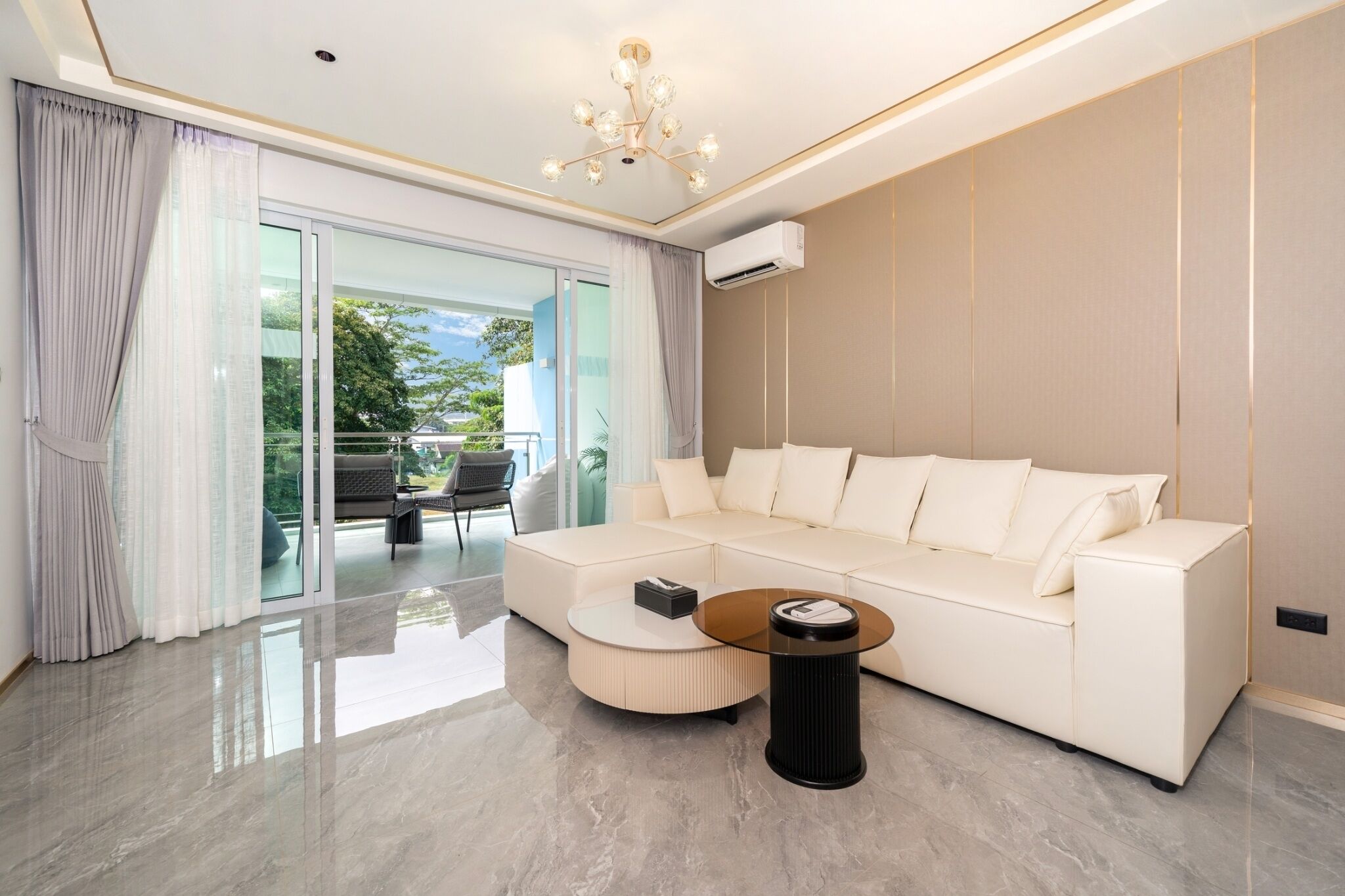 A modern living room with a white sofa, a round coffee table, and a chandelier.