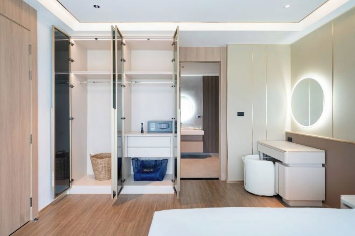 A modern bedroom with a walk-in closet, a vanity with a mirror, and a bedside table.