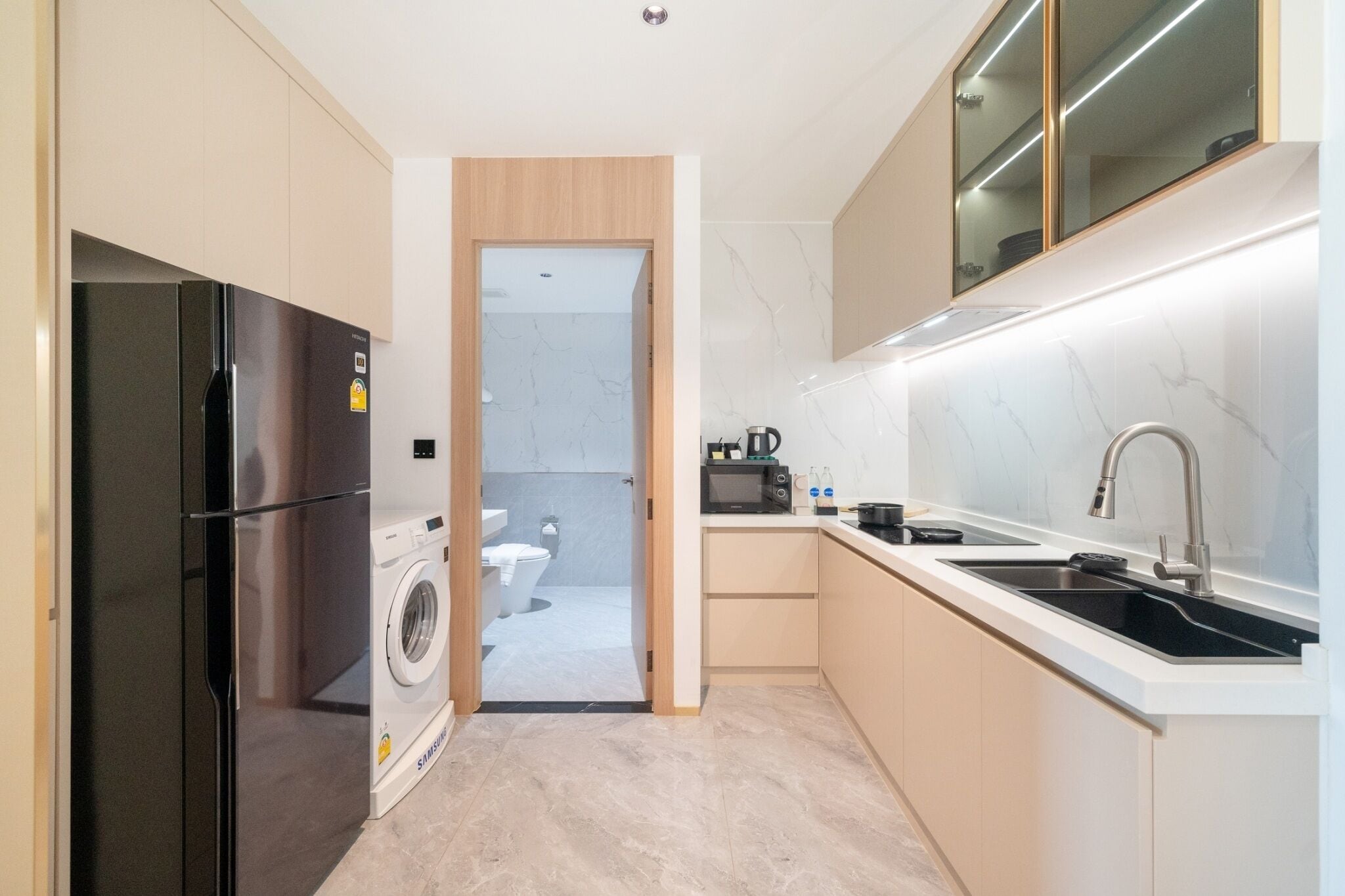 Een moderne keuken met een ingebouwde wasmachine, een magnetron en een spoelbak.