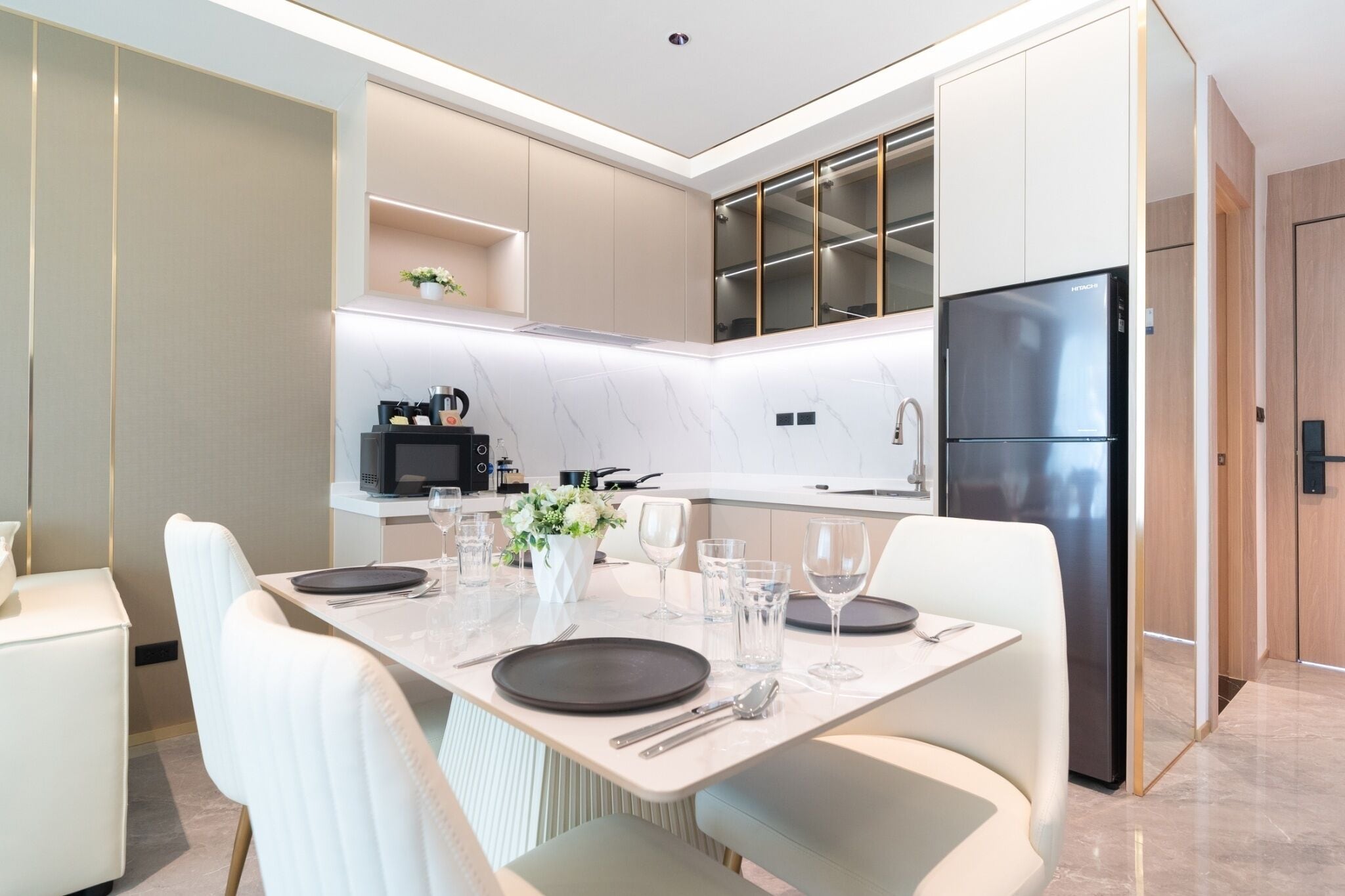 A modern kitchen with a built-in microwave, refrigerator, and a dining area with a table set for four.