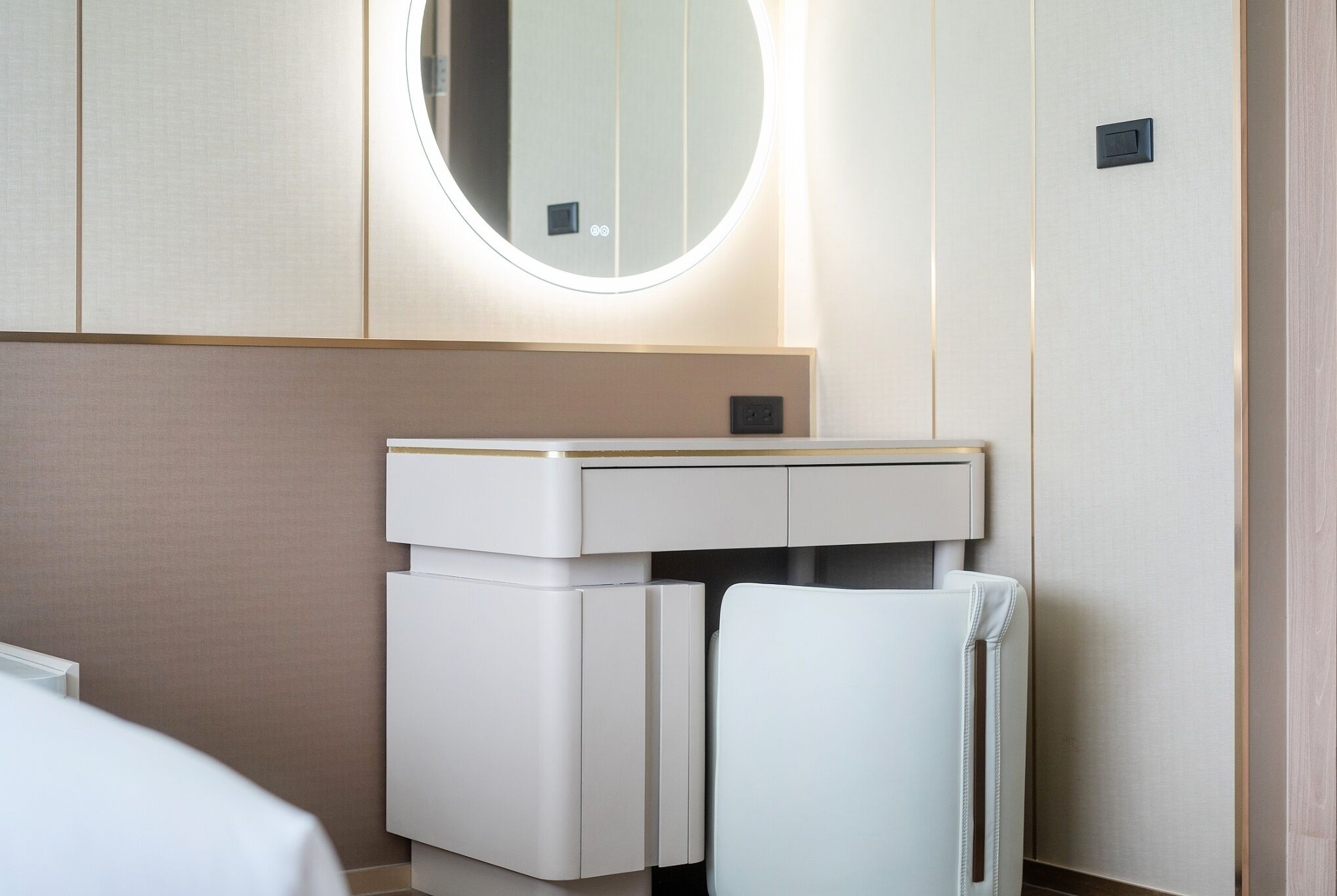 Un baño moderno con un espejo redondo, un lavamanos blanco y un perchero para toallas.