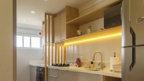 Una cocina moderna con lavavajillas integrado, electrodomésticos de acero inoxidable y un estante superior de madera.