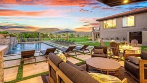A poolside area with lounge chairs, a fire pit, and a dining table.