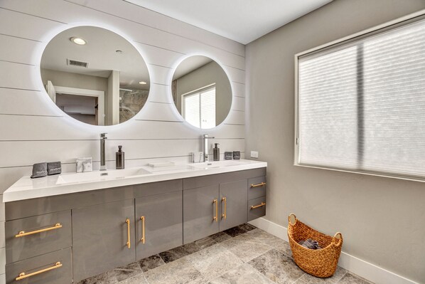 Une salle de bain moderne avec deux lavabos, un grand miroir et une fenêtre.