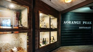 Interior de restaurante con paneles de madera y vitrinas de vidrio que exhiben vajillas y botellas.