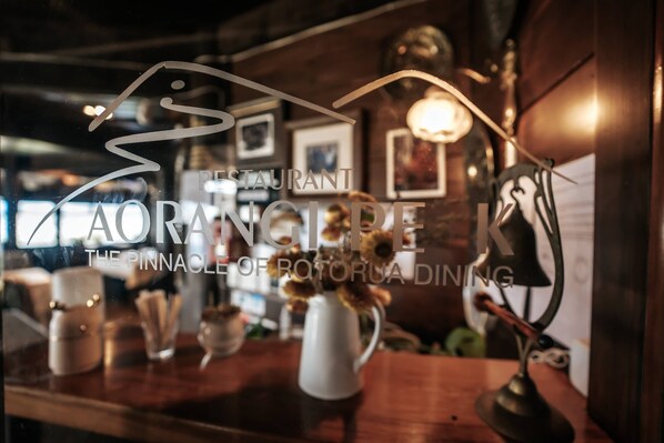 A restaurant interior with a wooden counter, decorative vases, and framed pictures on the wall.