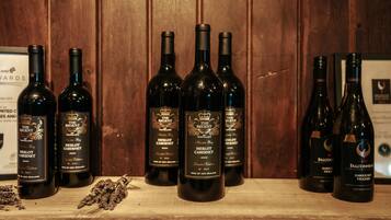 A wooden shelf with several bottles of wine, including 'The Regent Merlot Cabernet 2020' and 'Falconhead Hawke Bay Viognier 2020'.