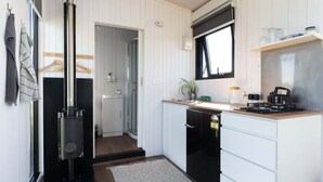 Een compacte keuken met witte kastjes, een zwart fornuis en een klein raam.