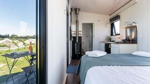 Een moderne kamer met een bed, een kleine kitchenette en uitzicht op een wijngaard.