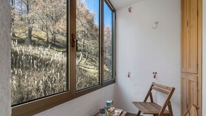 Un balcon donnant sur une forêt, une table avec une tasse, une théière et une assiette remplie de nourriture.
