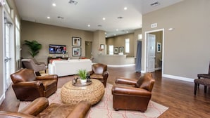 A spacious living area with leather sofas, a round coffee table, and a television.