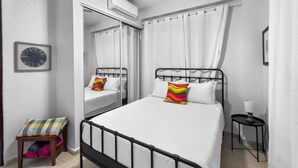 Ein Schlafzimmer mit Bett, Spiegel, Nachttisch und Stuhl.