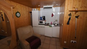 A compact kitchen with wooden walls, a microwave, a coffee maker, and a sink. - Holiday Home 'Zum Pferdestall' with Shared Pool, Shared Terrace and Wi-Fi (Dreetz)