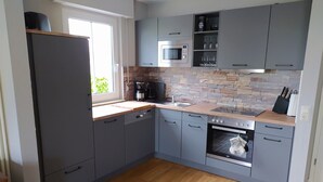 Una cocina moderna con gabinetes grises, horno integrado, microondas y cafetera.