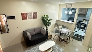 A modern living room with a sofa, a dining table with chairs, and a small potted plant.