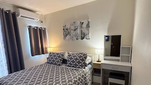 A bedroom with a bed, a desk, and a chair.
