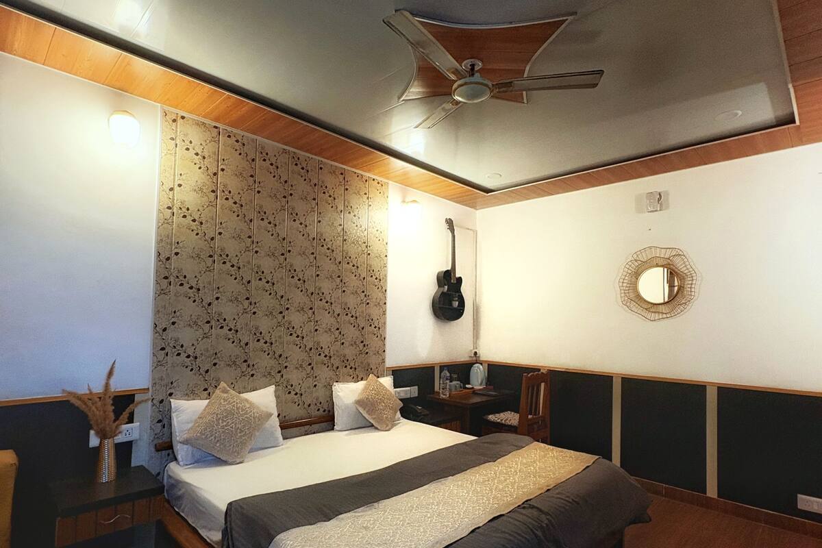 A modern bedroom with a large bed, a ceiling fan, a guitar, and a mirror on the wall.