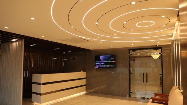 A modern reception area with a digital display, a reception desk, and a seating area. - BLOFT HOTEL (Katpadi)