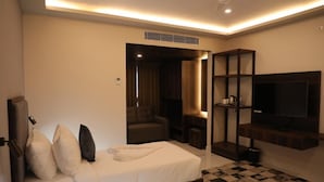 A hotel room with a bed, a TV, a seating area, and a small table. - BLOFT HOTEL (Katpadi)