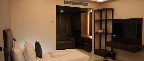 Una habitación de hotel con cama, televisor, zona de estar y una mesita.