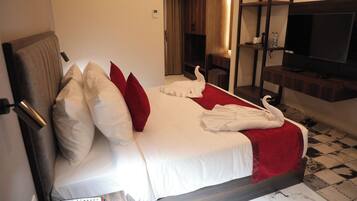Una habitación de hotel con cama, televisión, mesita de noche y espejo.