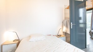 A bedroom with a bed, bedside tables, a wardrobe, and a door leading to a balcony. - Bright apt 4/6 ppl, balcony, nears the slopes (Chamrousse)