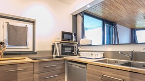 A modern kitchen with wooden cabinets, a dishwasher, a microwave, and a sink. - Bright apt 4/6 ppl, balcony, nears the slopes (Chamrousse)