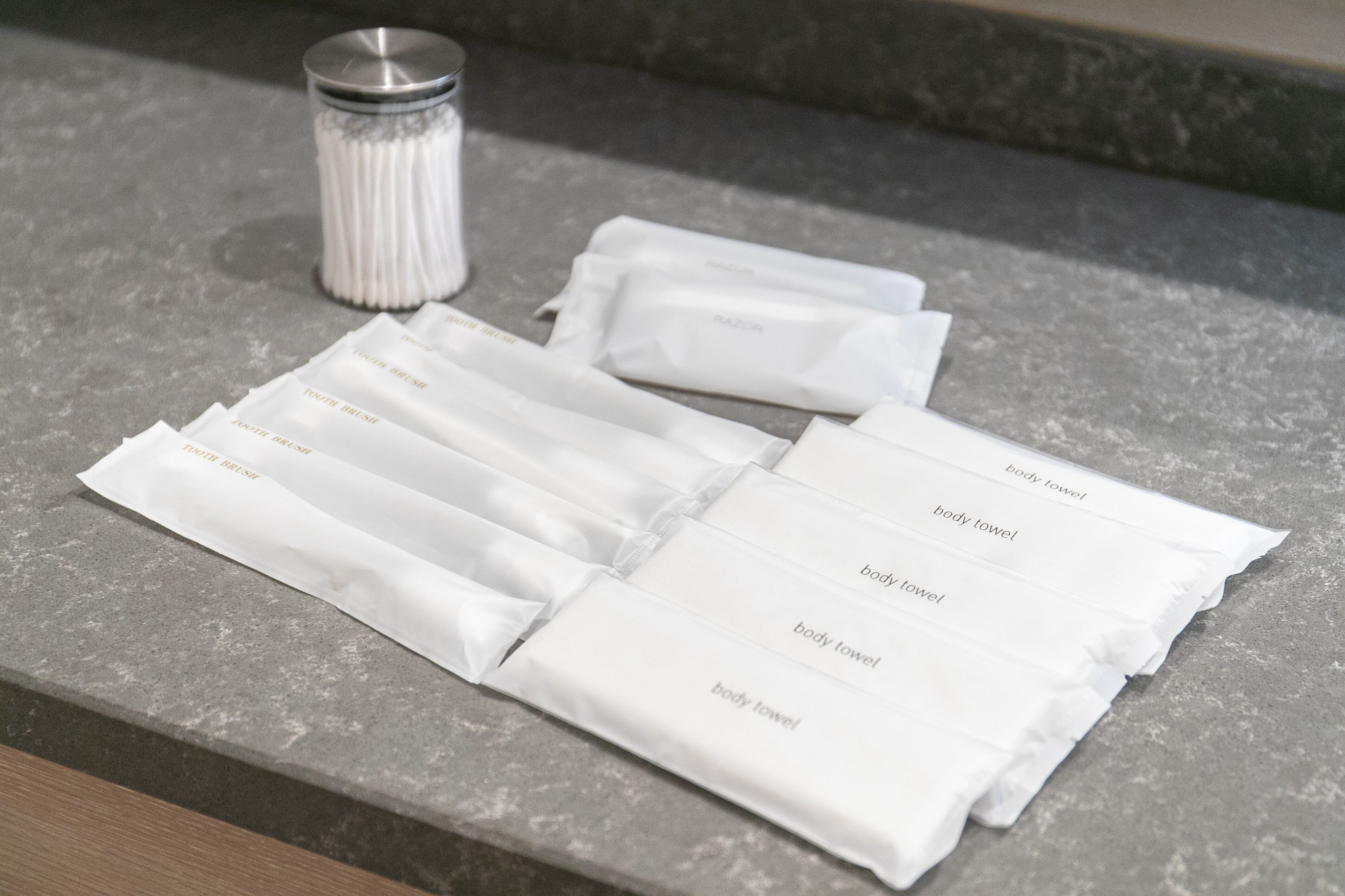 A set of white body towels on a stone countertop.