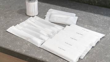A set of white body towels on a stone countertop.