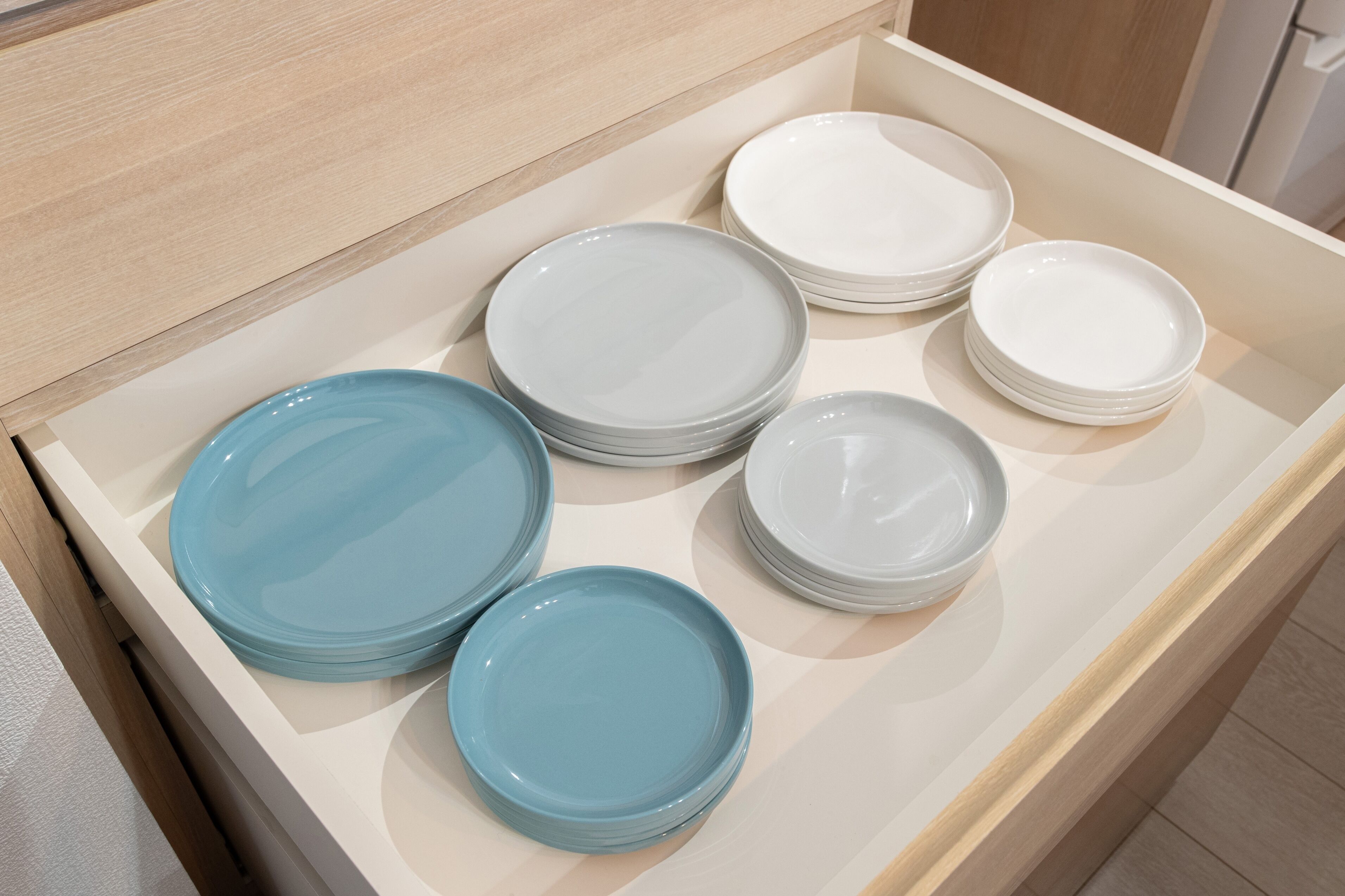 A drawer with neatly stacked plates in various colors.